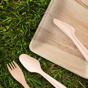Rustic outdoor dinner featuring Natural Palm Leaf Square Plates with fresh greens and sustainable cutlery accents.
