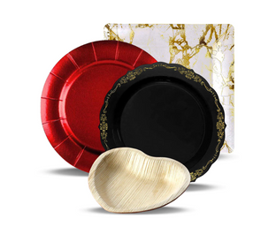 A collection of four different plates: a round, metallic red plate; a round black plate with an ornate gold rim; a heart-shaped beige plate; and a square plate with a white and gold marbled pattern. The plates are arranged overlapping each other.
