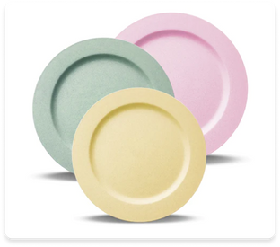 Three circular plates are arranged overlapping each other. The plates are in pastel colors: a green plate slightly in the back, a pink plate to its right, and a yellow plate in the front. The plates are on a plain white background.