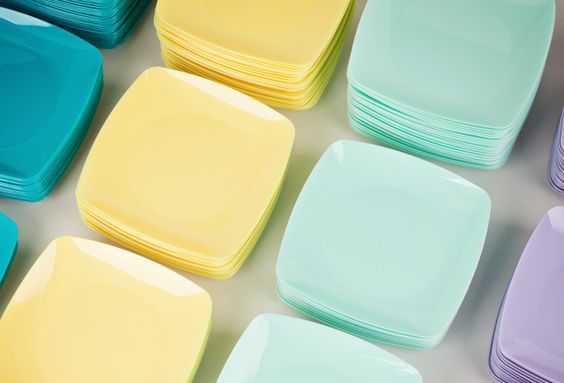 A collection of stacked plates in assorted colors, emphasizing the importance of determining how many dinnerware sets you should have.