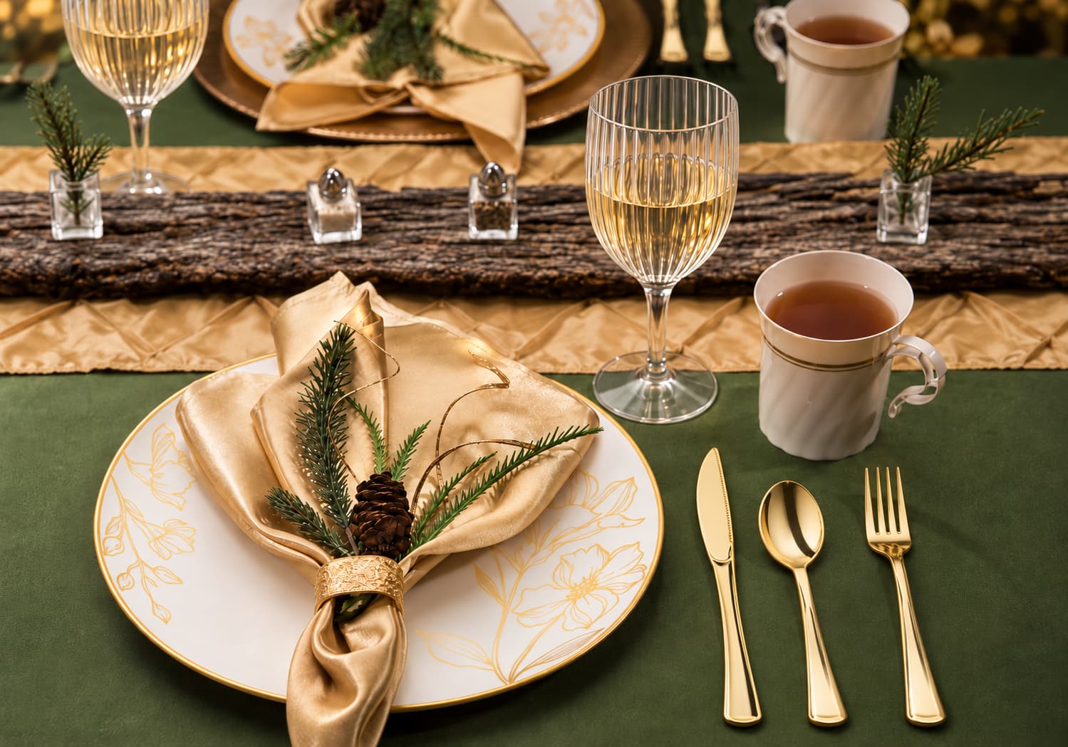 Elegant fall tablescape with white and gold floral plates, ribbed wine glasses, gold flatware, and green table decor.