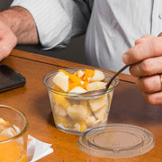 1.5 oz clear souffle cups with lids filled with dips and dressings at a catering station, tidy disposable portion control for buffets and events.
