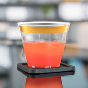 9 oz. Clear with Metallic Gold Rim Round Disposable Plastic Cups used during a modern celebration with appetizers and drinks