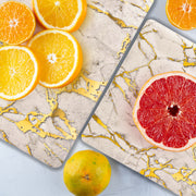 Chic square charger plates with gold marble detail on a rustic table surrounded by natural foliage décor.