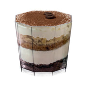 A vertical close-up of a glass containing a layered dessert, resembling tiramisu. Distinct layers of cream, coffee-soaked sponge, and cocoa powder on top are visible. Two coffee beans garnish the top layer. The clear 5.5 oz. Octagon Disposable Plastic Dessert Cup boasts an octagon design, enhancing its geometric, faceted appeal.