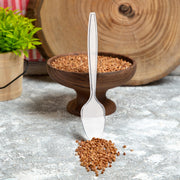 Clear medium heavy weight plastic teaspoons set beside plates at a party table, sleek disposable flatware for weddings, showers, and receptions.
