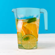 Clear round 52 oz plastic pitchers filled with infused water and lemonade at a drink station, stylish disposable servers for showers and receptions.
