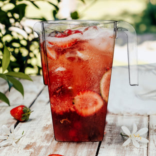 Cocktail station display showing 52 oz. Clear Square Plastic Disposable Pitchers with wine, snacks, and ambient light