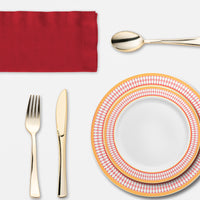 Cozy dining setup with laughter, golden cutlery, and red-rimmed plates highlighting a fall feast..
