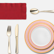 Cozy dining setup with laughter, golden cutlery, and red-rimmed plates highlighting a fall feast.