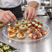 Crystal-clear 14-inch round plastic tray filled with assorted appetizers at a wedding reception