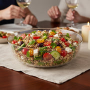 Crystal clear plastic salad bowl with metallic gold rim, stylish disposable tableware for professional catering and party food presentation.