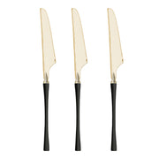 Disposable gold Moderno plastic dinner knives with black handles designed for easy cleanup at casual gatherings.
