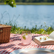 Elegant blush pink stemless plastic glass with gold rim on a modern coffee table, chic disposable drinkware for home parties.