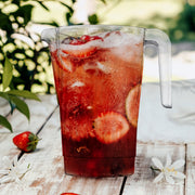 Guest pouring from a 52 oz clear round plastic disposable pitcher at a party bar, easy-pour beverage server for weddings and outdoor gatherings.
