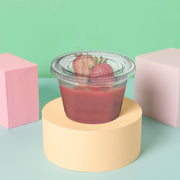 Guests picking up sealed 1.5 oz clear portion cups at a grab-and-go counter, hygienic disposable souffle cups with lids for single-serve condiments.
