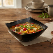 Guests served from 128 oz black wave square disposable bowls at a catered gathering, sleek plastic serveware for effortless entertaining and cleanup.
