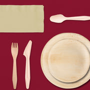 Outdoor Thanksgiving meal served with palm leaf plates and clear stemless wine glasses under string lights.