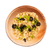 Palm leaf mini bowl filled with fresh hummus and cucumber slices, ideal for healthy individual servings