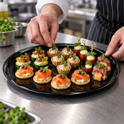 Perfect for wedding dessert tables, these 18" Black Round Plastic Trays keep cupcakes, cookies, and petit fours organized in style.