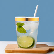Premium clear plastic tumbler with gold rim used for iced coffee, chic and sturdy disposable tableware for professional catering.