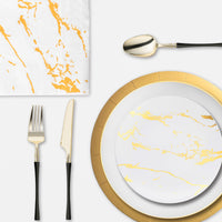 Reception dinner setup with sparkling glassware, gold-trimmed plates, and matching cutlery under warm lights.