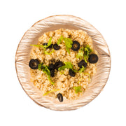 A top view of a bowl of quinoa salad garnished with slices of black olives and fresh parsley. The quinoa is light and fluffy, and the vibrant green parsley adds a touch of color against the beige quinoa. The rustic, textured bowl is one of our Round Palm Leaf Eco Friendly Mini Disposable Dip Bowls (0.5 oz.), adding sustainability to your meal.