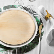 Round palm dinner plates styled on a boho-themed table with greenery runners and bamboo cutlery.