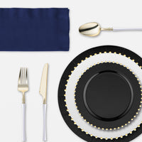 Sophisticated table setting with contrasting plates and elegant metallic accents.