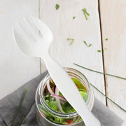 White plastic serving forks resting beside chafing dishes on a buffet line, clean disposable serveware for weddings, showers, and holiday parties.
