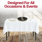 White tablecloth and gold-rimmed dishes in the Dear Santa Set shine in a candlelit setting.