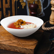 White with Silver Rim Organic Round Disposable Plastic Soup Bowl filled with creamy soup, garnished with cheese slices.